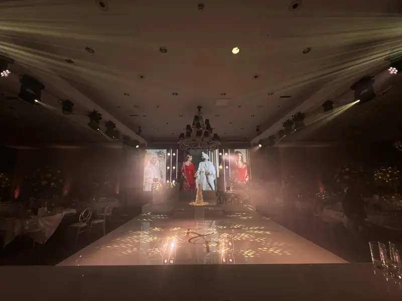 Wide view of a reception with three LED screens and stage lighting